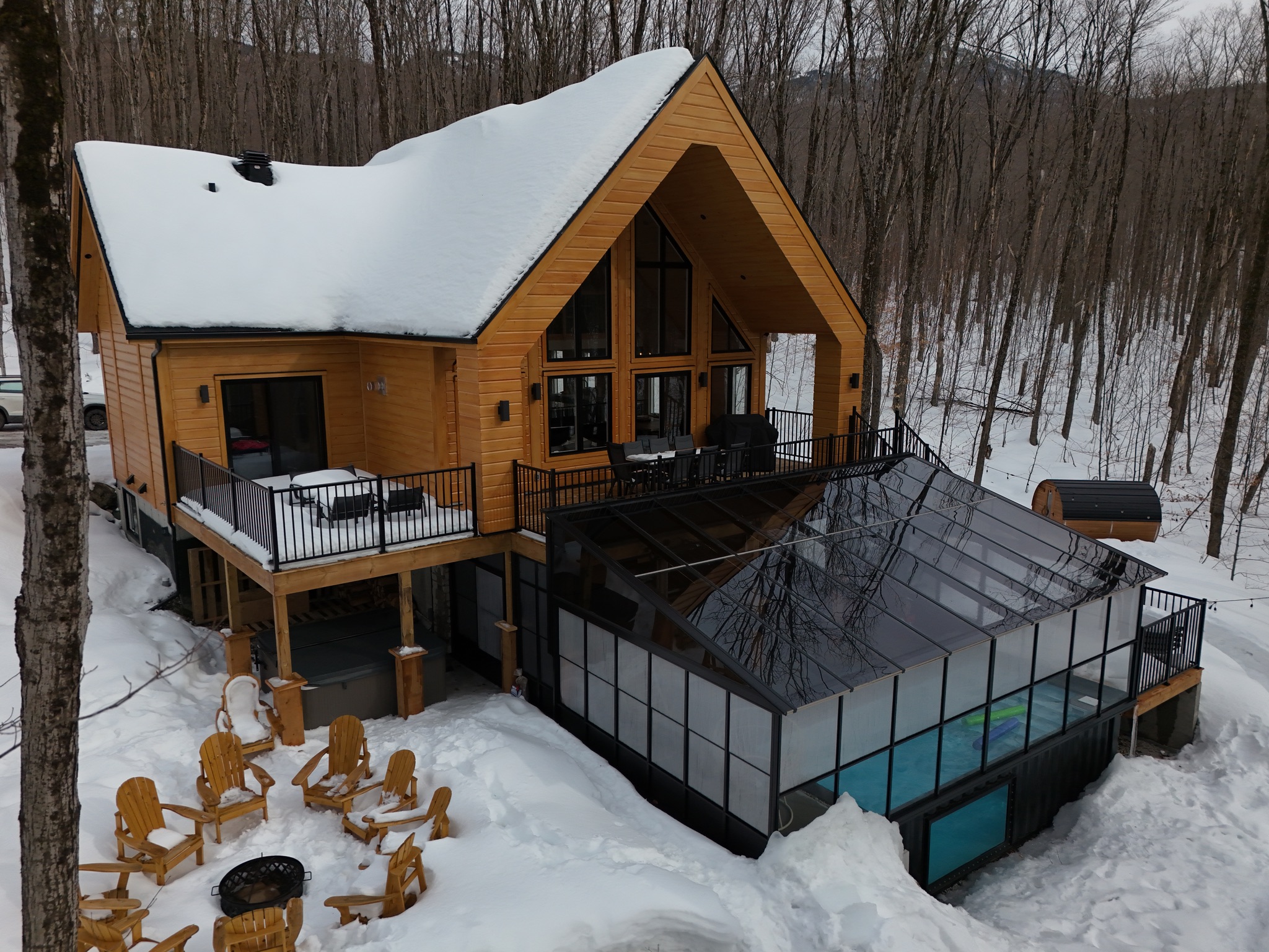 Vue aérienne hivernale du chalet, du solarium, de la piscine et du sauna dans la forêt