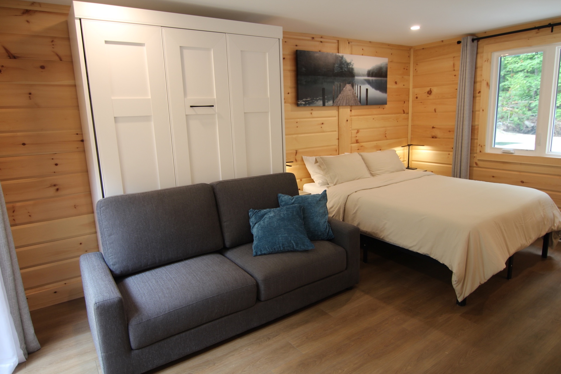 Chambre spacieuse avec lit, canapé-lit et vue sur la forêt