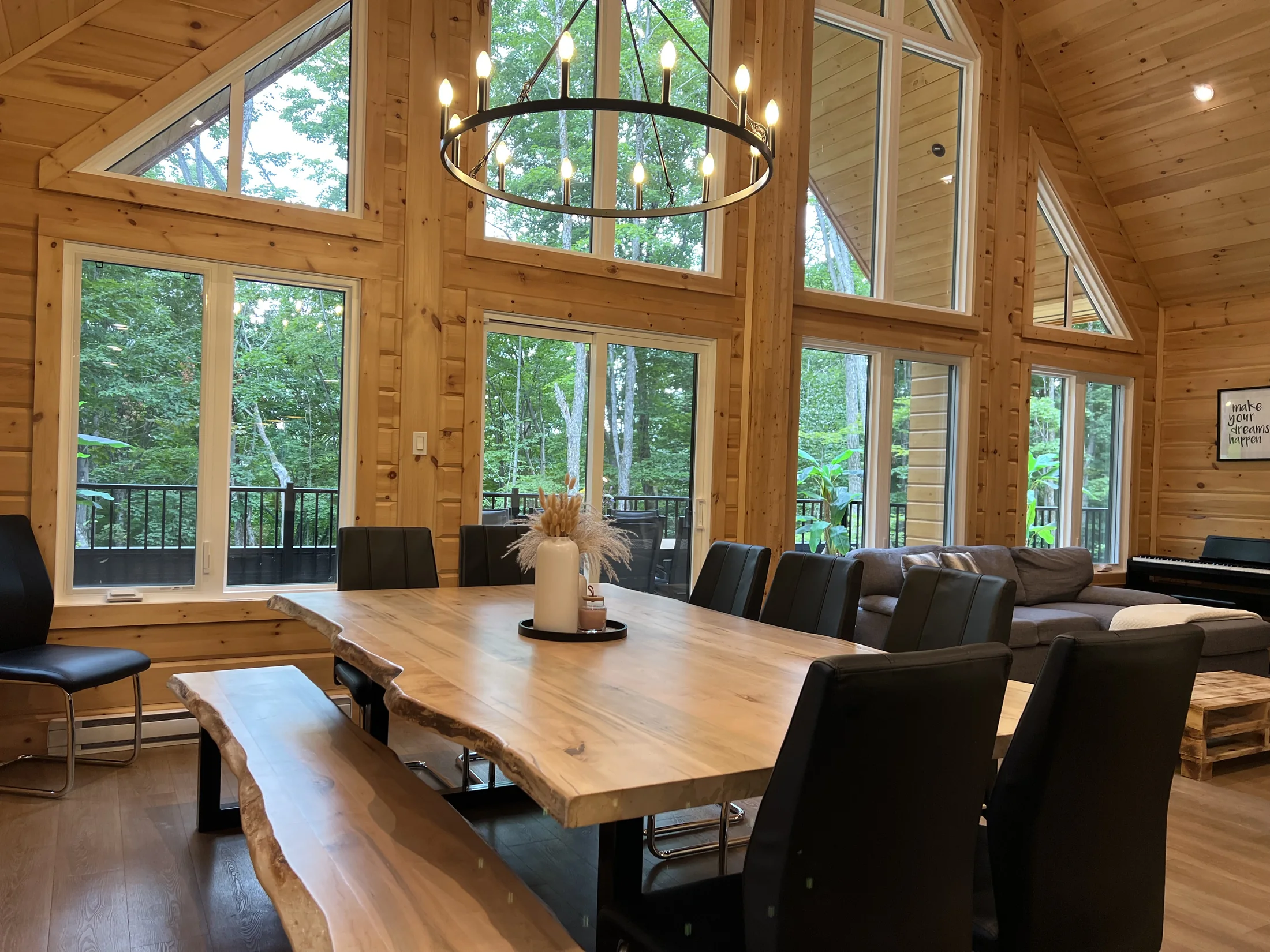 Grande table conviviale et fenestration donnant sur la forêt en été