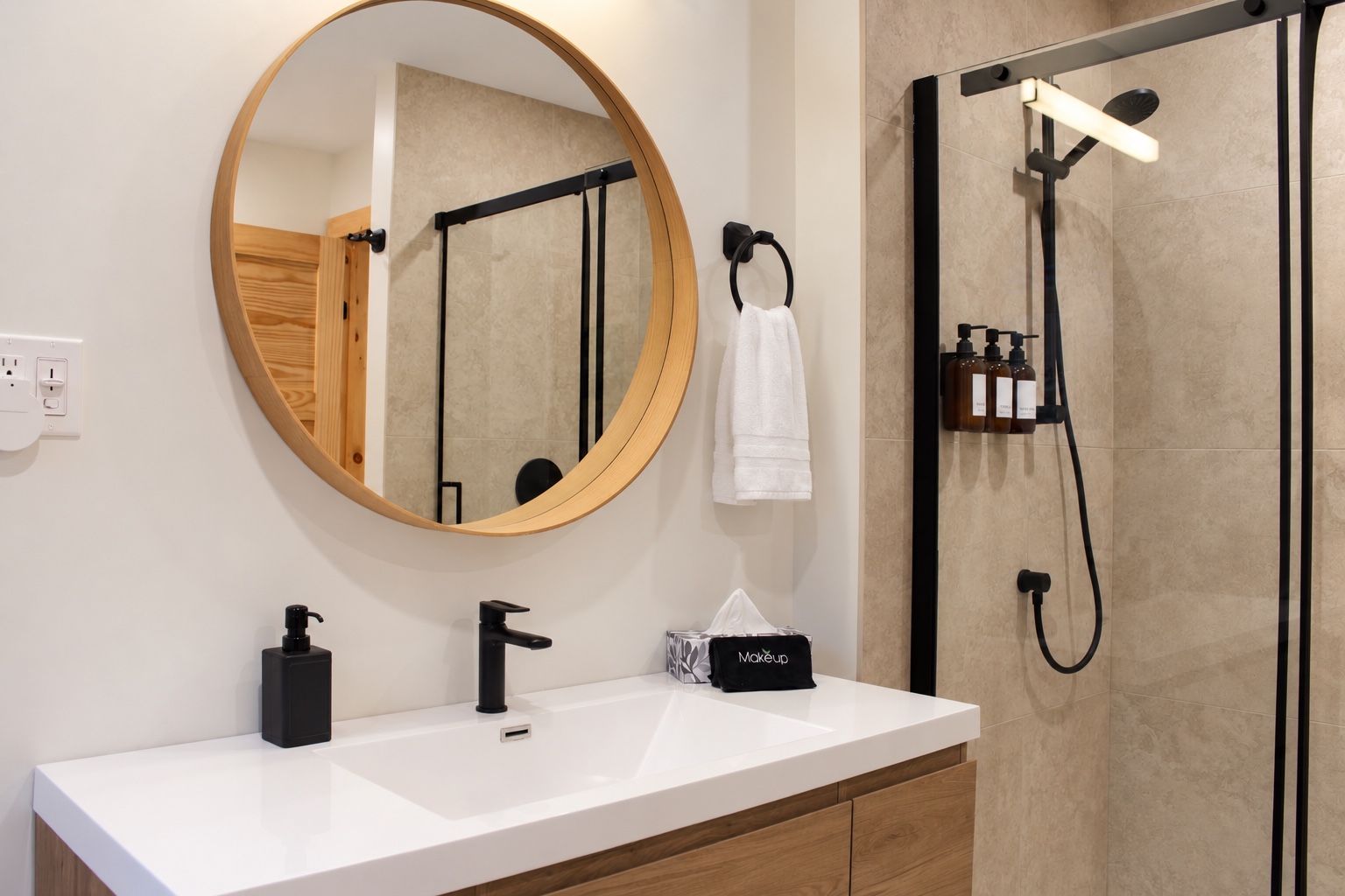 Troisième salle de bain avec meuble-lavabo, miroir rond et douche vitrée