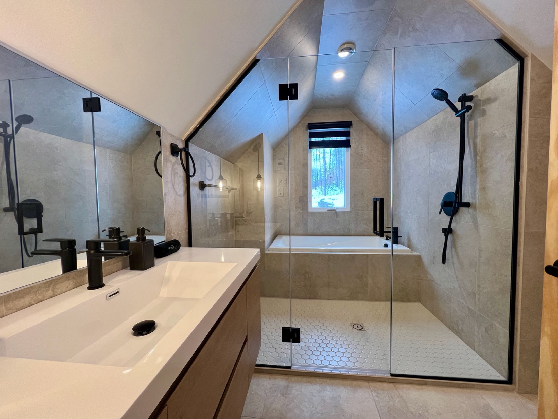 Deuxième salle de bain mansardée avec baignoire et grande douche vitrée