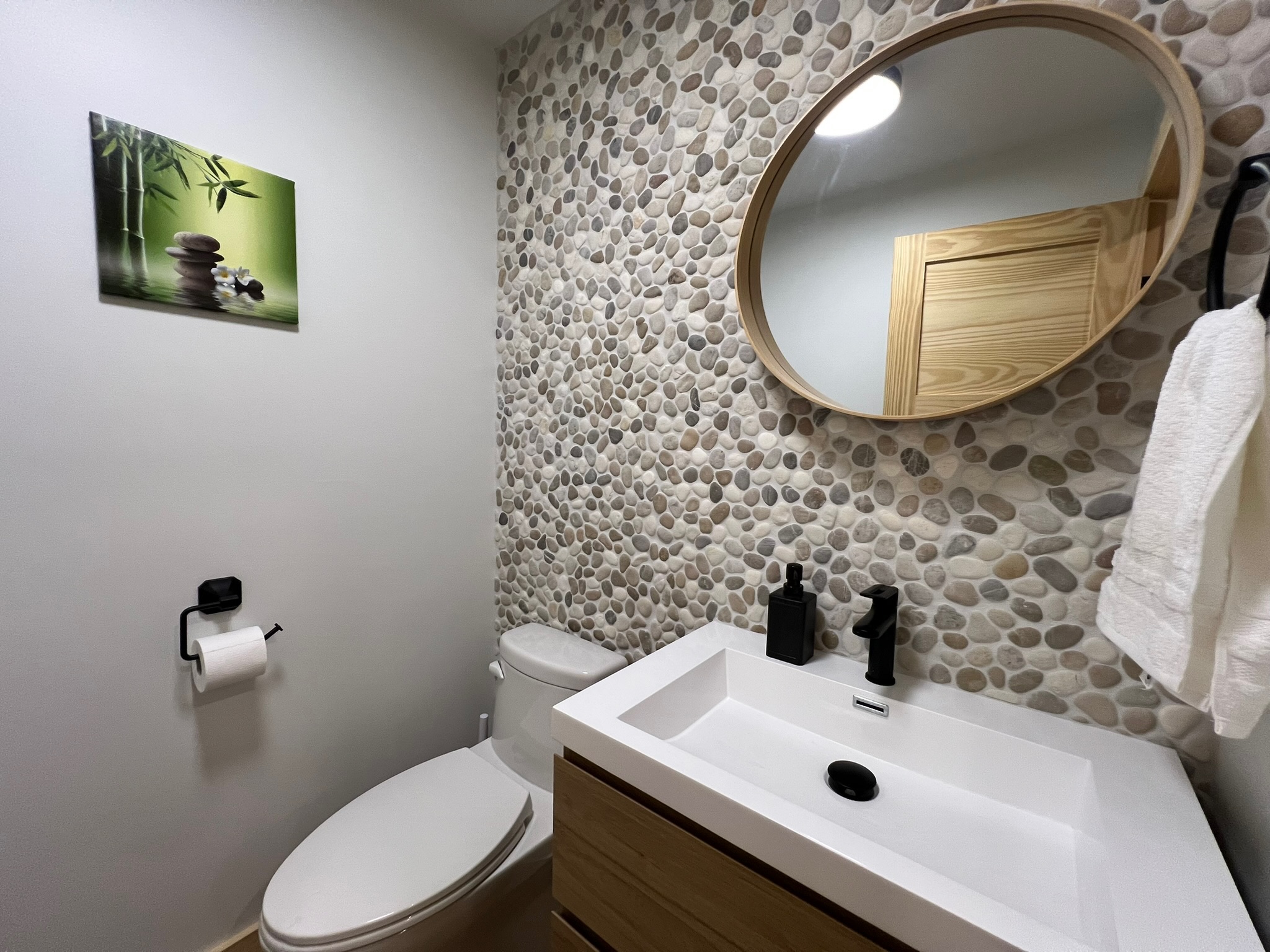 Salle d’eau avec mur de pierres naturelles, miroir rond et meuble-lavabo