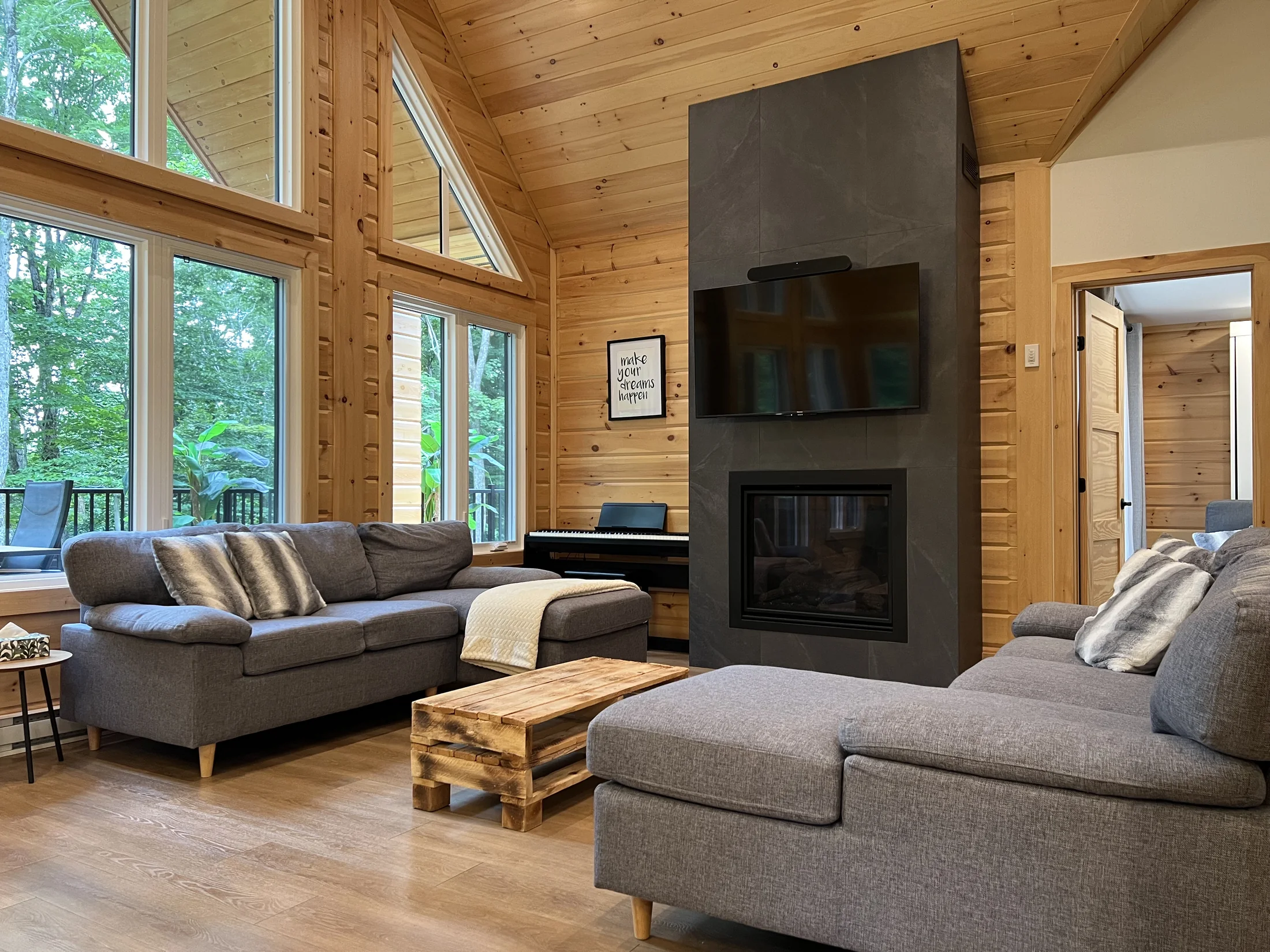 Salon lumineux avec foyer, grande fenestration et vue sur la forêt