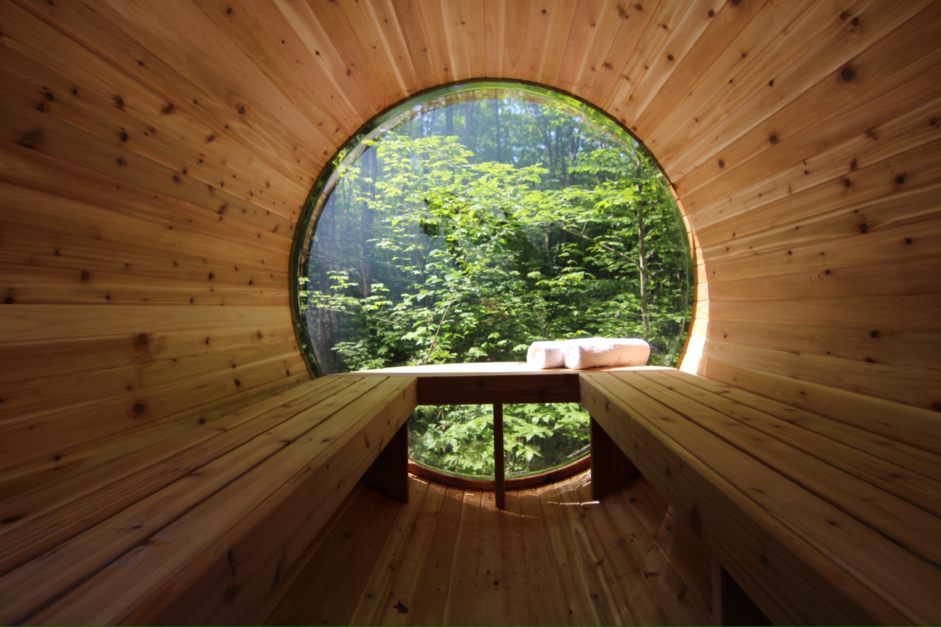 Intérieur du sauna boréal avec deux serviettes roulées et vue sur la forêt
