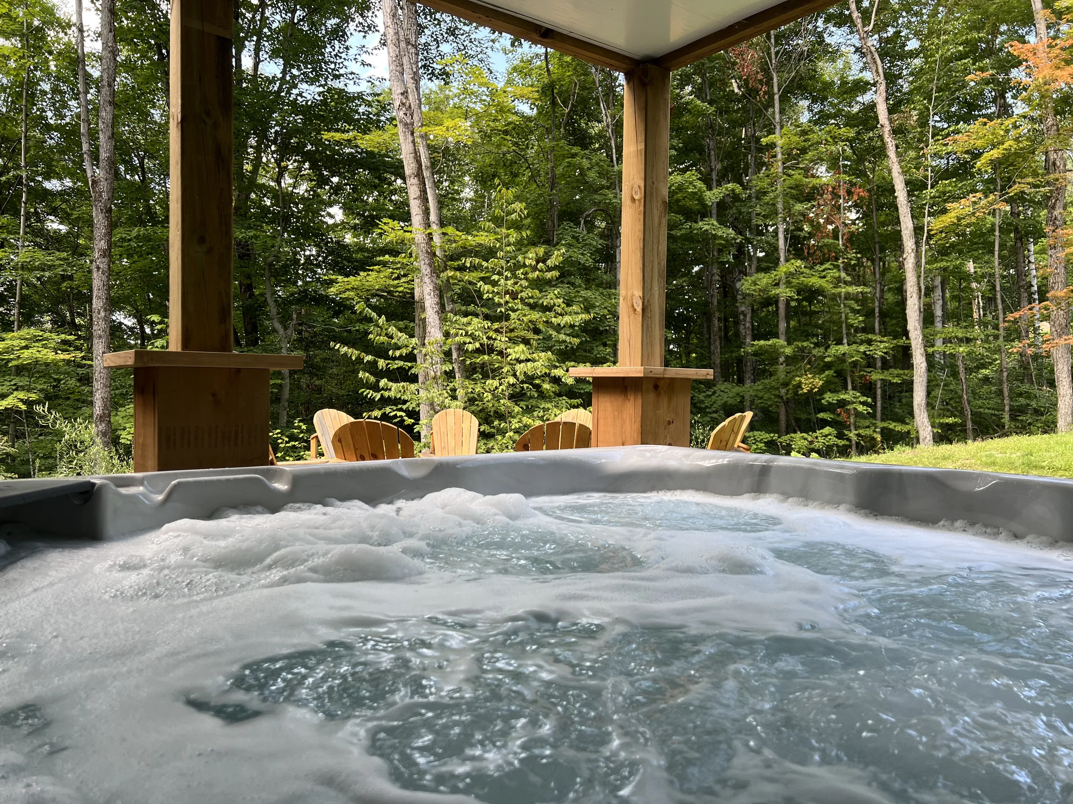 Spa extérieur avec les jets en fonction et vue sur la forêt